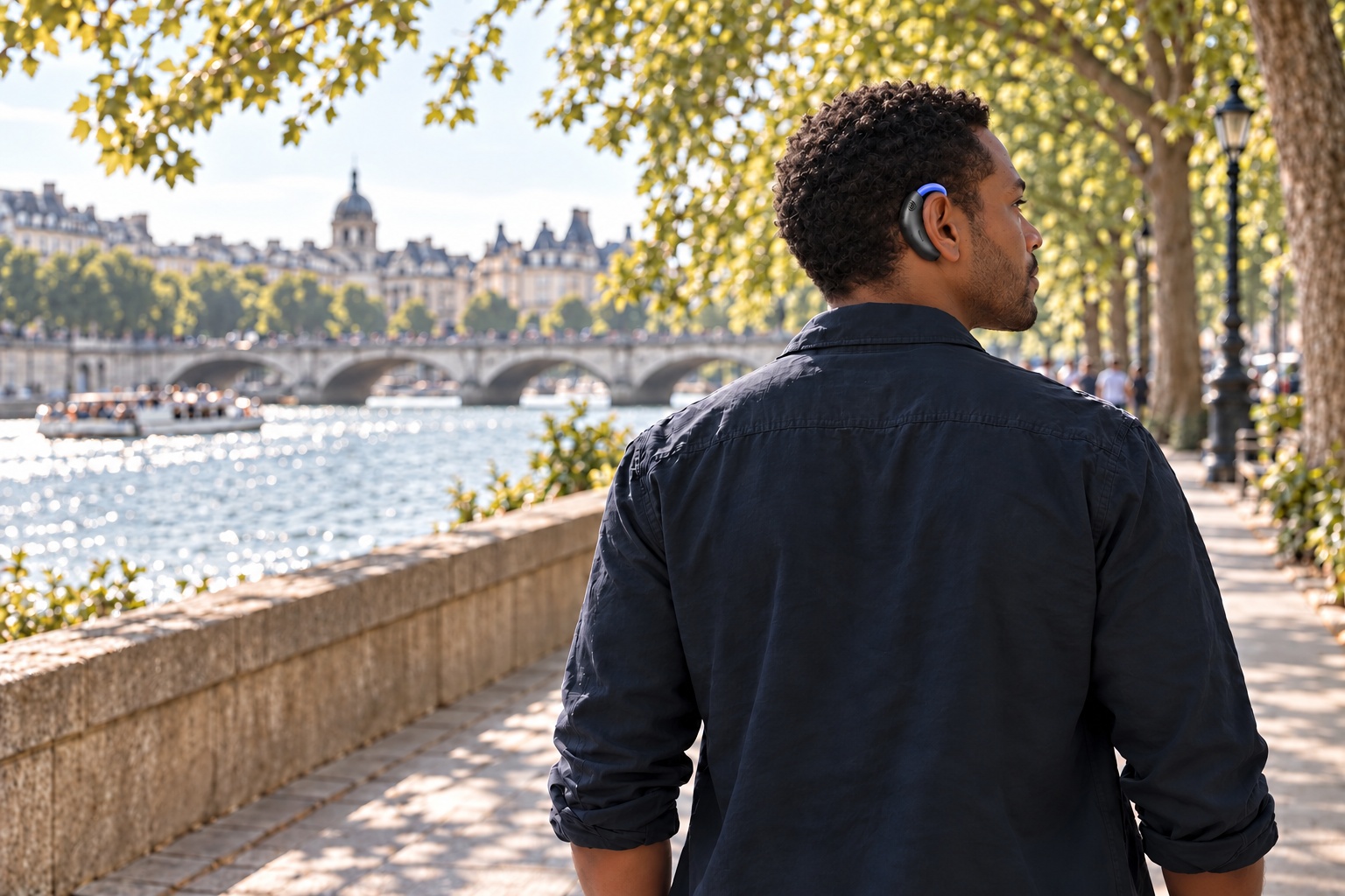 A man wearing blue Jalapeño, seen from behind, looks toward the river during an unhurried walk