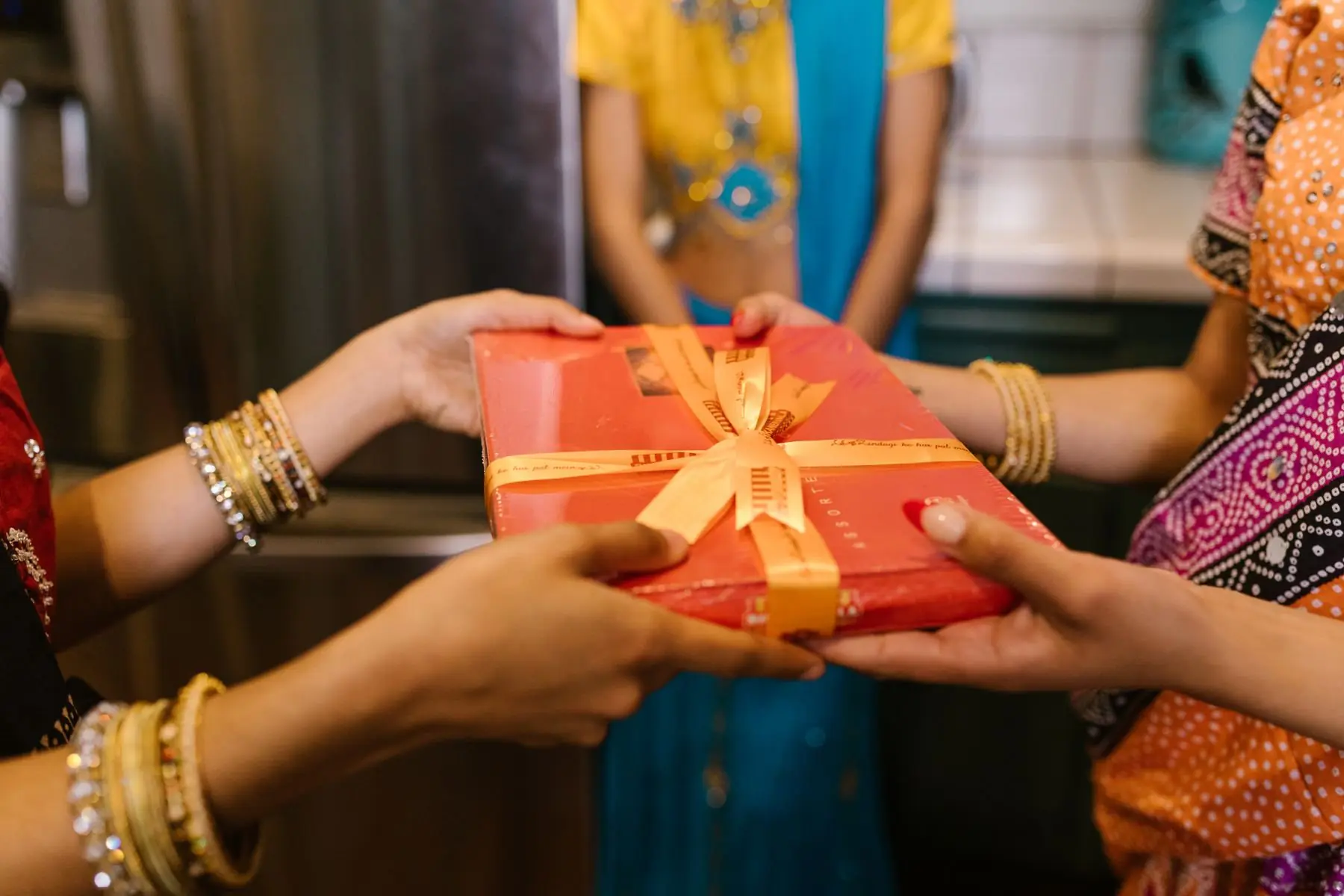 Two pairs of hands passing a wrapped gift