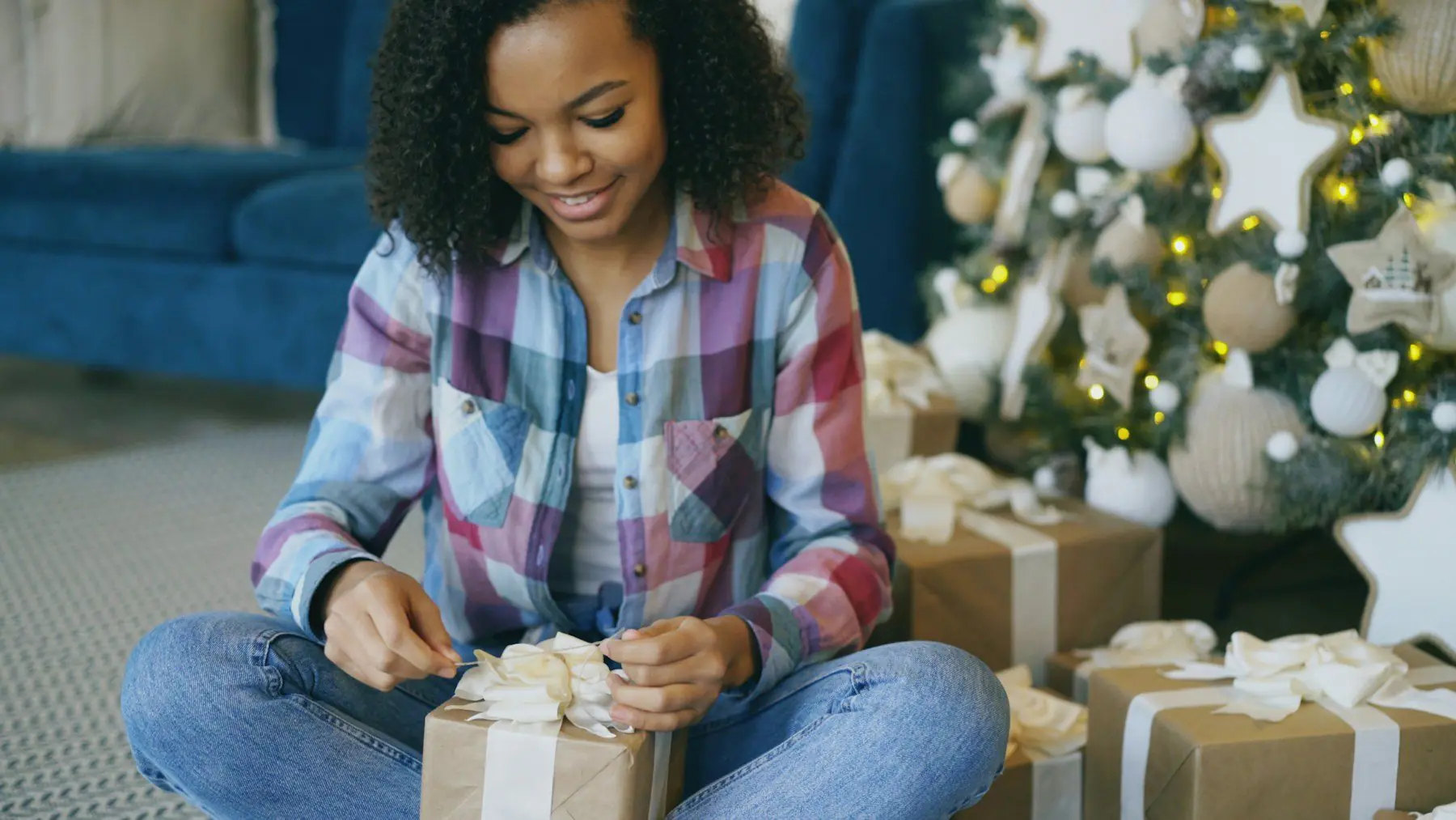 A young woman smiling as she unties a wrapped gift